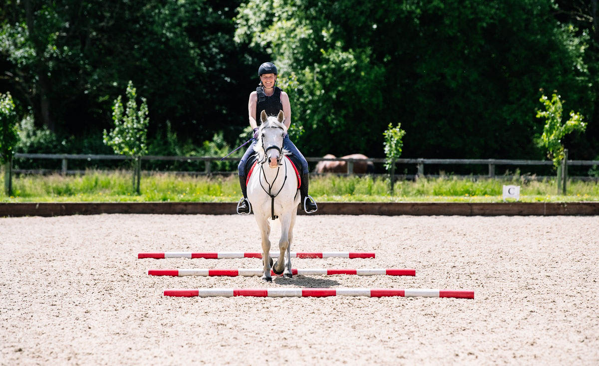equestrian-smiling-whilst-practicing-in-a-horse-riding-arena