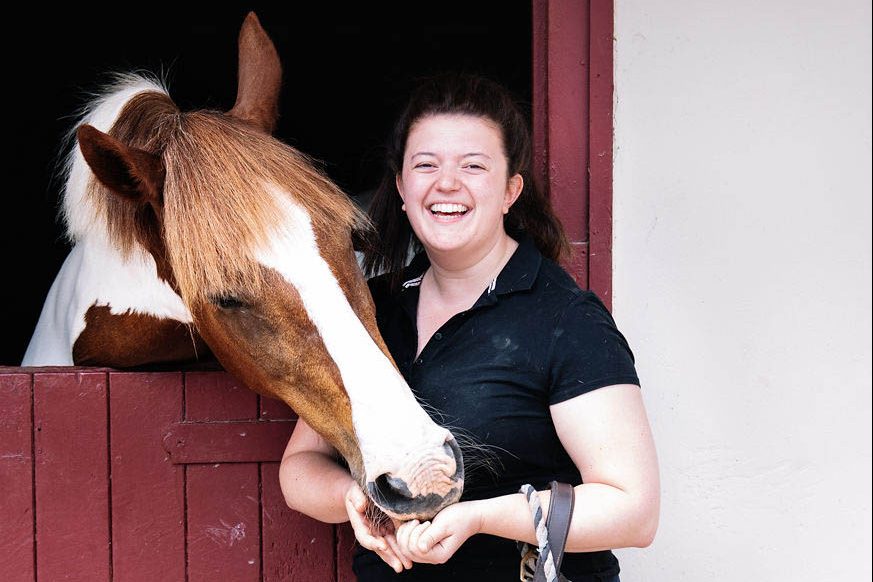 horse-rider-petting-their-brown-and-white-horse-in-a-stable
