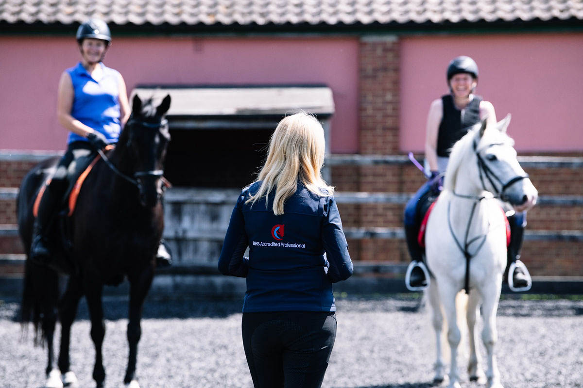horse-riders-being-trained-in-a-paddock-by-a-riding-instructor