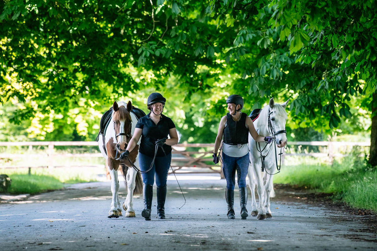 horse-riders-smiling-and-laughing-whilst-leading-their-horses