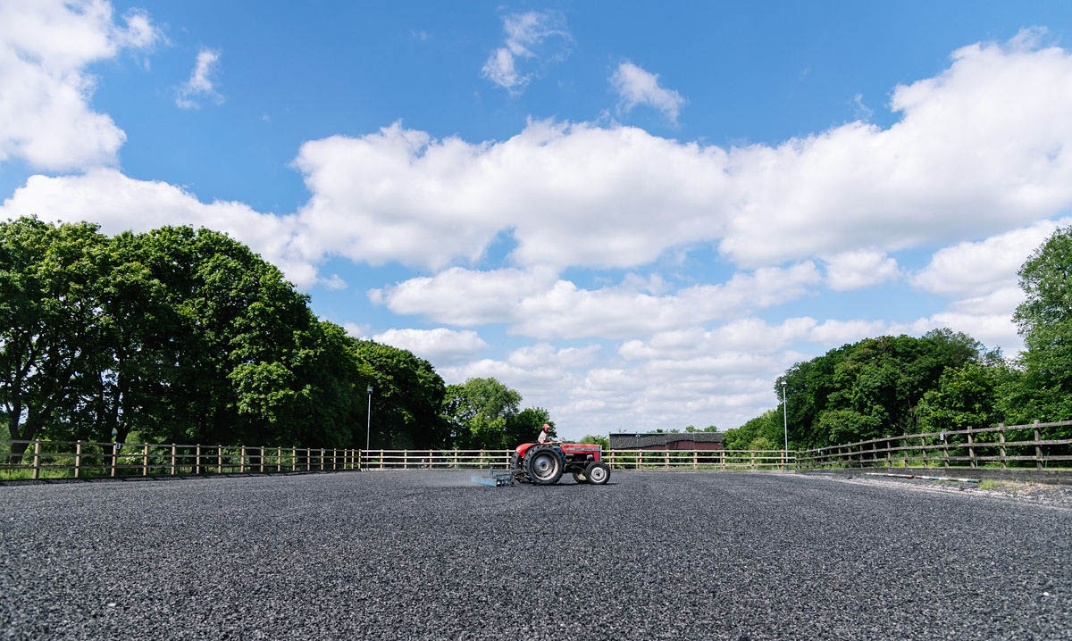 red-tractor-performing-maintenance-on-a-horse-arena